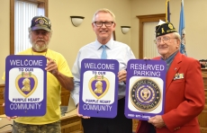 From left: Chuck Jones, administrative officer of the Department of Minnesota Purple Heart Organization, Lake City Mayor Mark Nichols, and Andru Peters, vice commander of American Legion District 1 with parking and welcome signs presented to the city at the Aug. 16 City Council meeting.